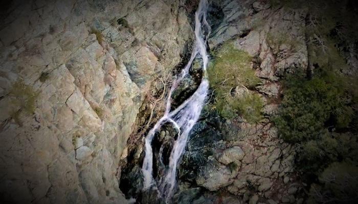 A drone follows the water falling from above at Chantara Waterfalls